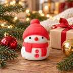 Snowman Squishy, Mochi Soft and Slow Rising (red), in a Christmas scene with fir branches and fairy lights