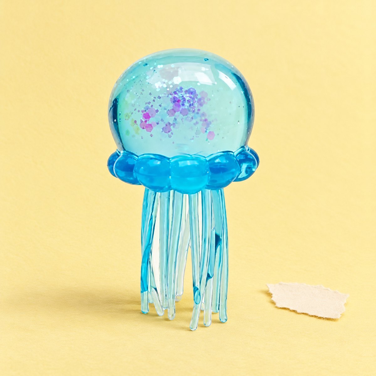 Squishy alforreca azul com brilhantes, em TPR macio, sobre papel pastel