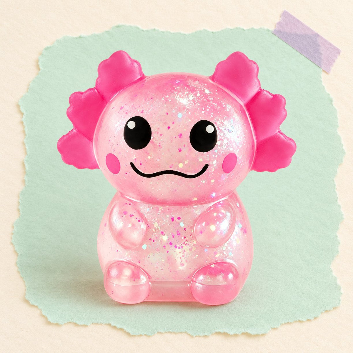 Třpytivý squishy axolotl v růžové barvě na pastelovém papíře