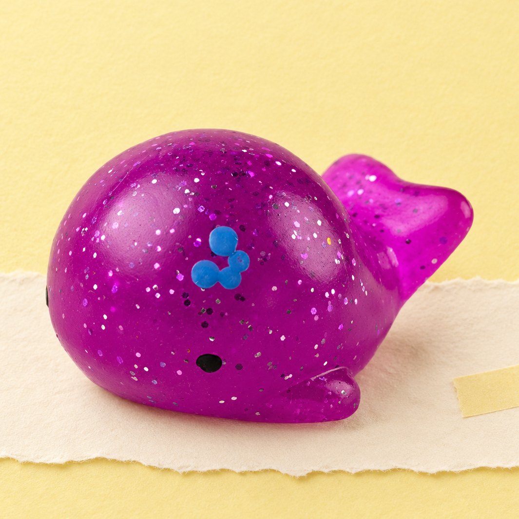 Squishy baleine mochi à paillettes, sur un papier pastel
