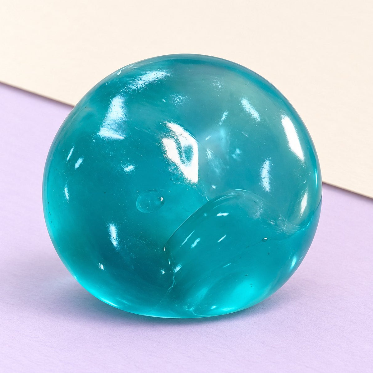 Squishy de maltosa: bola de gel slow rising en azul océano, sobre papel pastel