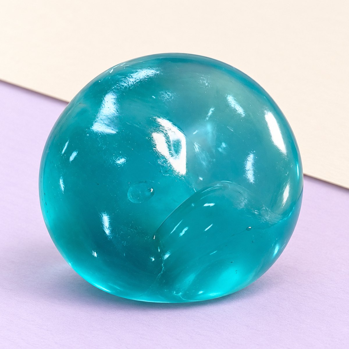 Squishy bola de maltose em gel, slow rising, cor azul-oceano, sobre papel pastel