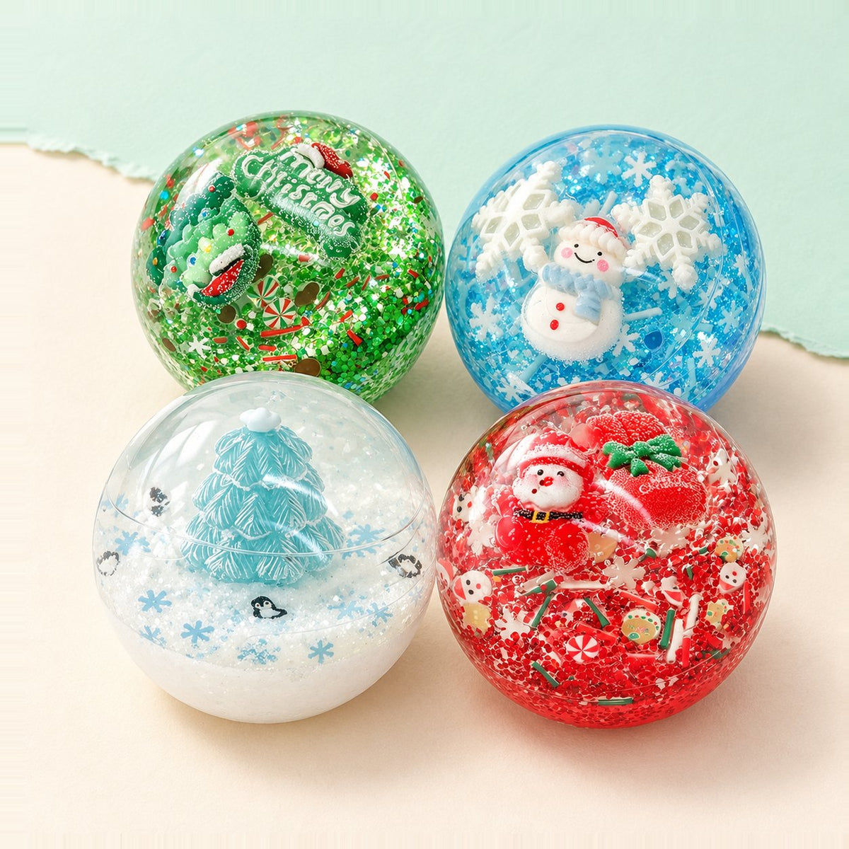 Set de squishy bola de Navidad con los 4 motivos, sobre papel pastel