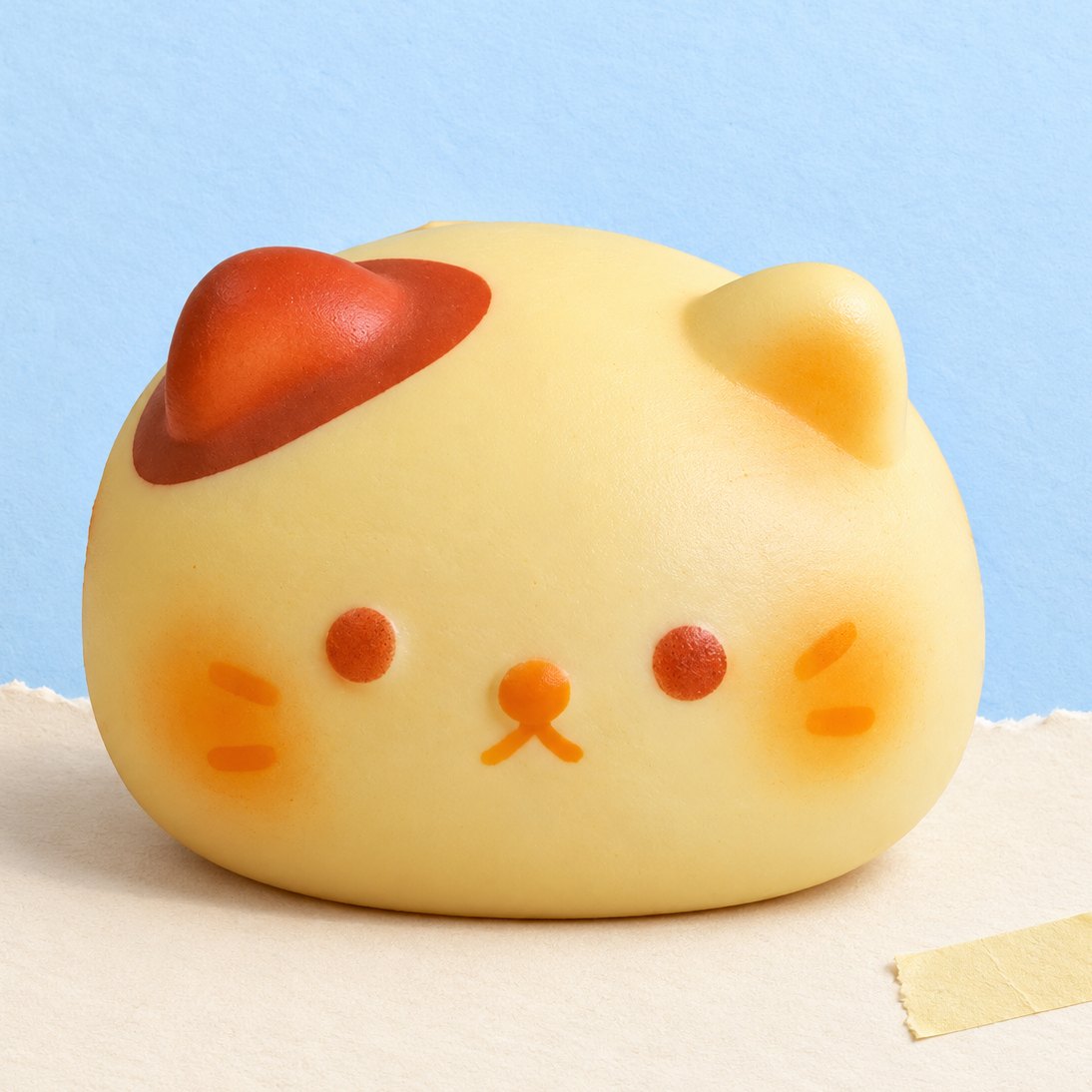 Squishy bollo gato, kawaii y slow rising, sobre papel pastel