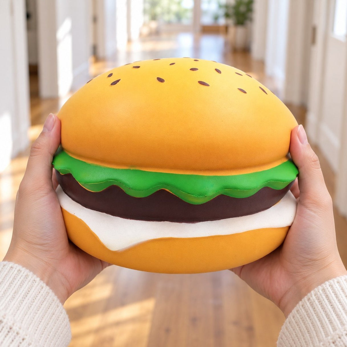 Squishy burger jumbo au sésame de 24 cm tenu à deux mains pour sa grande taille