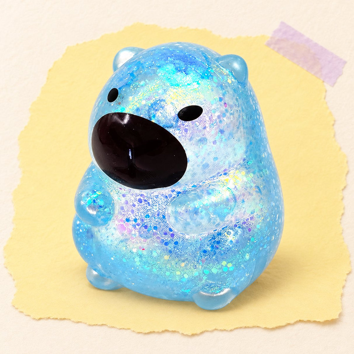 Squishy capibara blu con glitter fotografato su carta color pastello