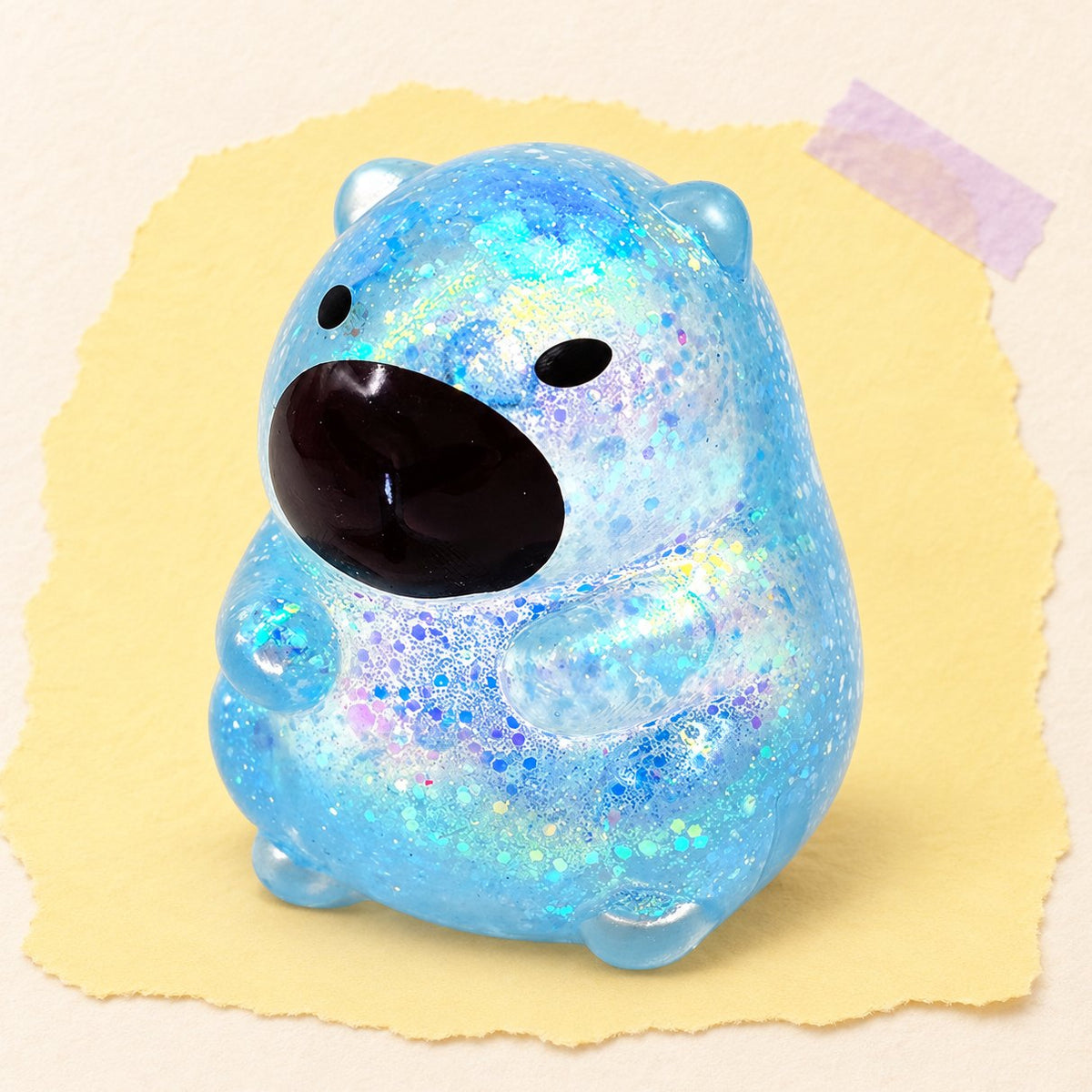 Squishy de capibara con purpurina, estilo sugar, en azul sobre papel pastel