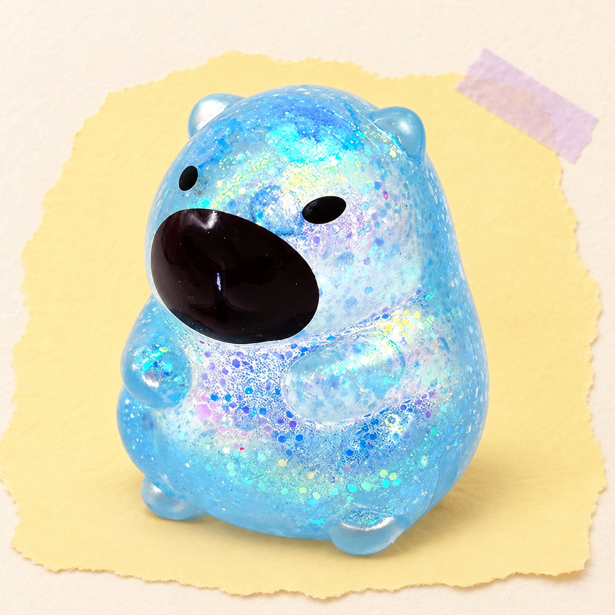 Squishy capivara com brilhantes, estilo sugar, em azul sobre papel pastel