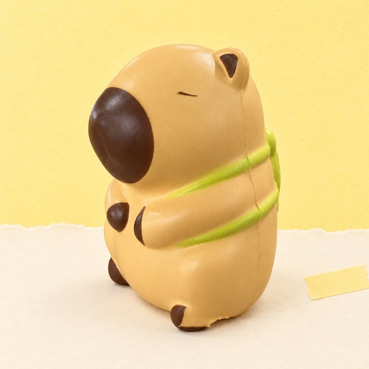 Squishy capybara slow rising beige clair avec sa tortue, posé sur un papier pastel