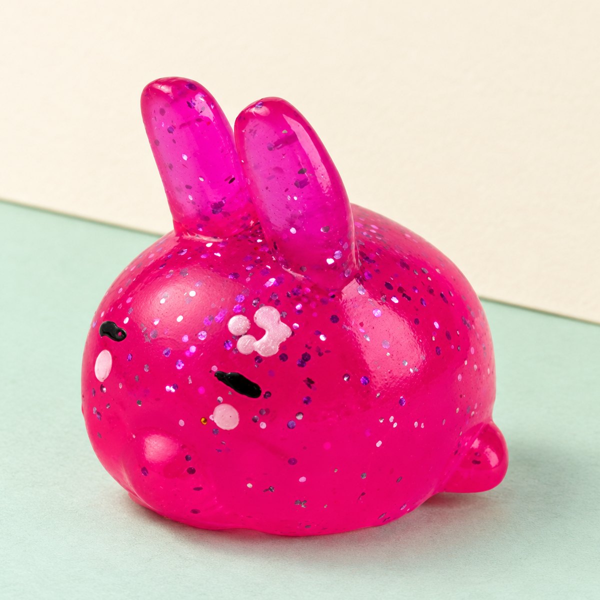 Squishy coelho mochi com brilhantes, sobre papel pastel
