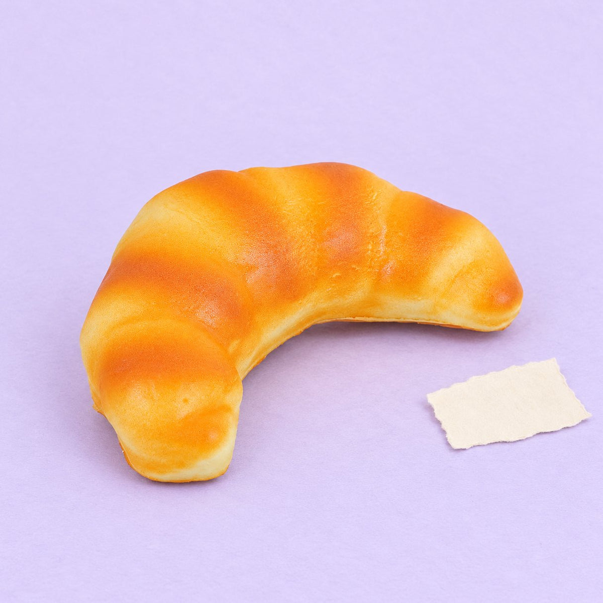 Squishy croissant doux, pain réaliste slow rising de 12,5 cm, sur papier pastel