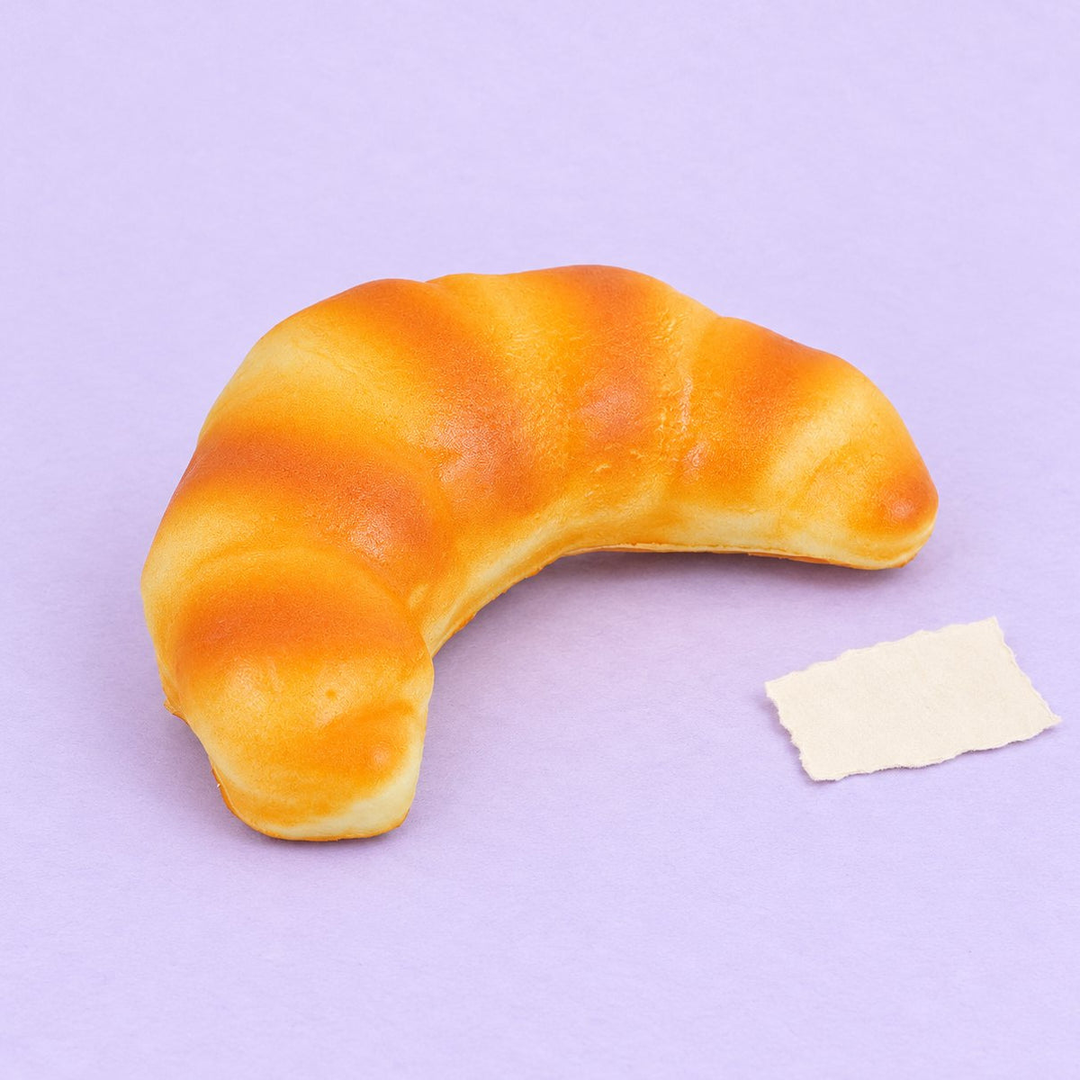 Squishy croissant realistico da 12,5 cm, foto del prodotto su carta pastello