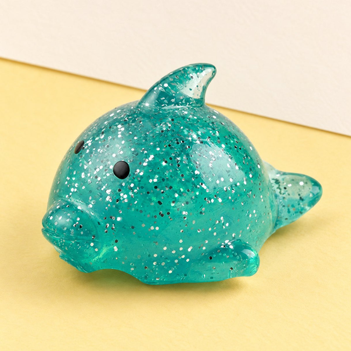 Squishy Delfin als großer Mochi mit Glitzer, Produktfoto auf Pastellpapier