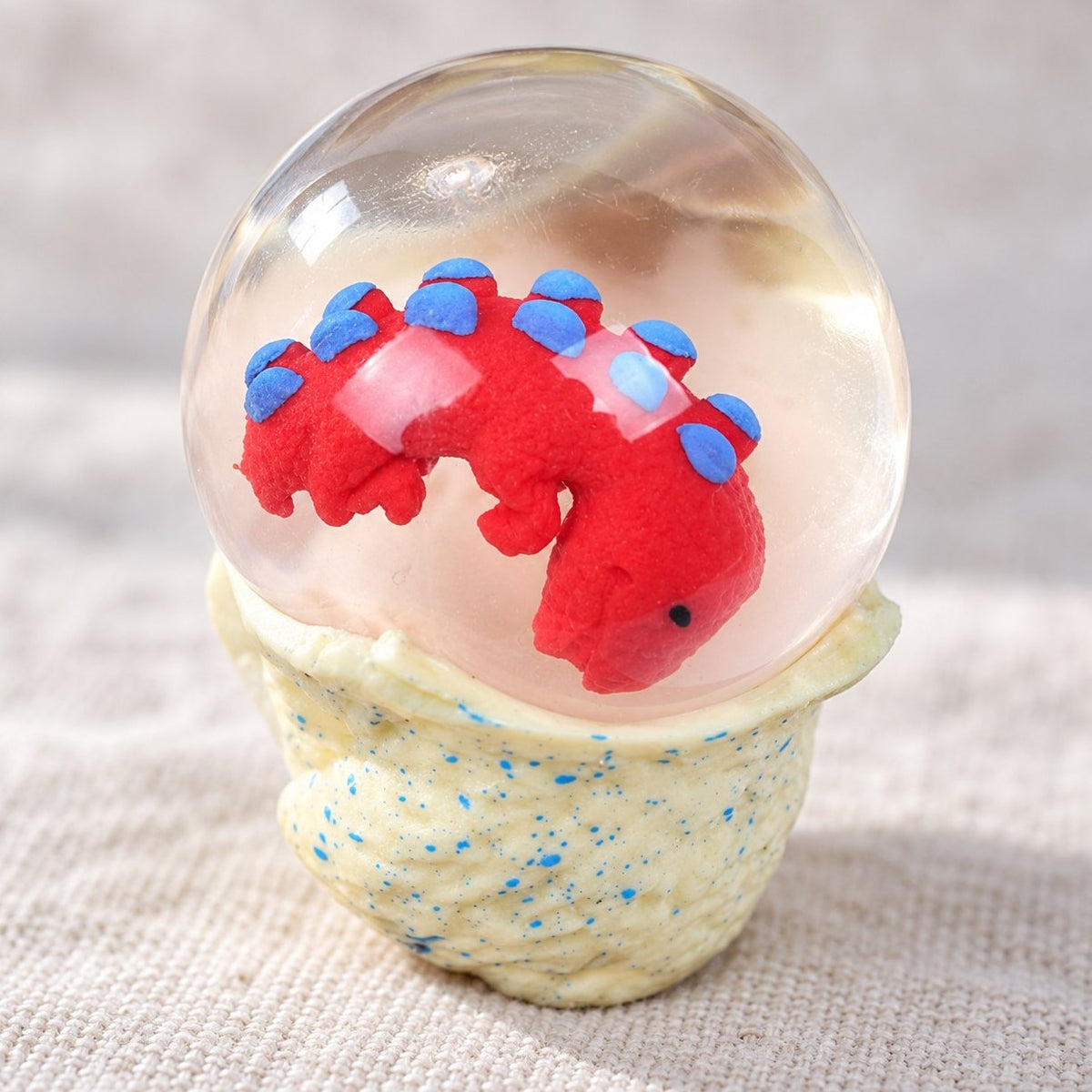 Detail povrchu a drobností zblízka: squishy dinosauří vejce, vodní koule s malým dinem