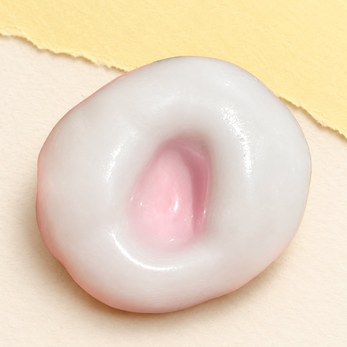 Squishy gâteau de riz mochi rose fraise, peau glacée extensible, sur papier pastel