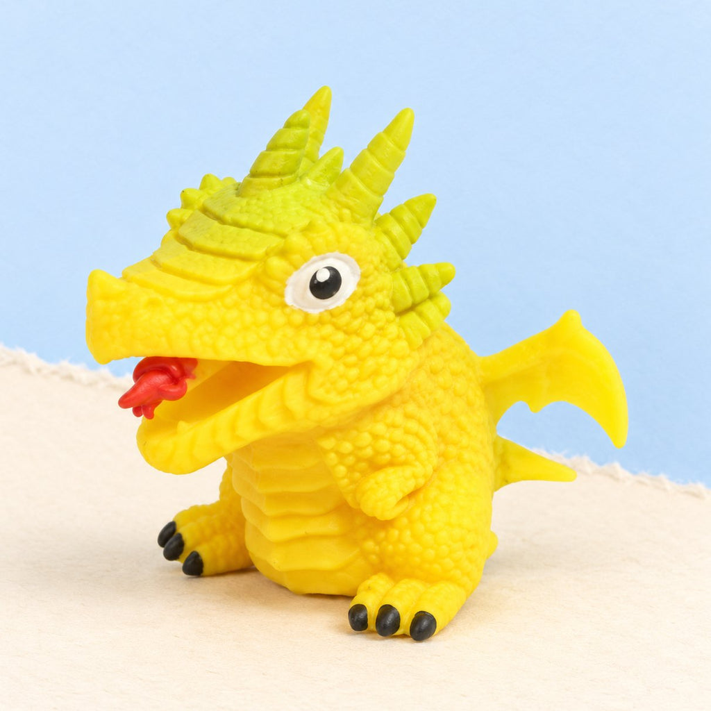 Squishy huevo de dinosaurio reversible amarillo, dino al azar, sobre papel pastel