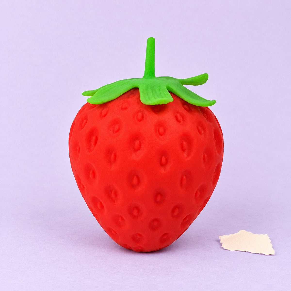 Squishy jahoda, obří a pomalu se zvedající, na pastelovém papíře