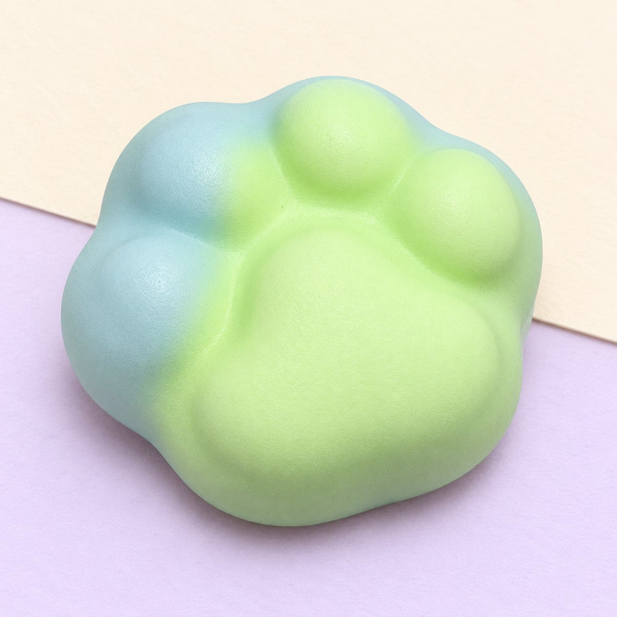 Zielony squishy łapka kota crunchy, 6 cm, na pastelowym papierze