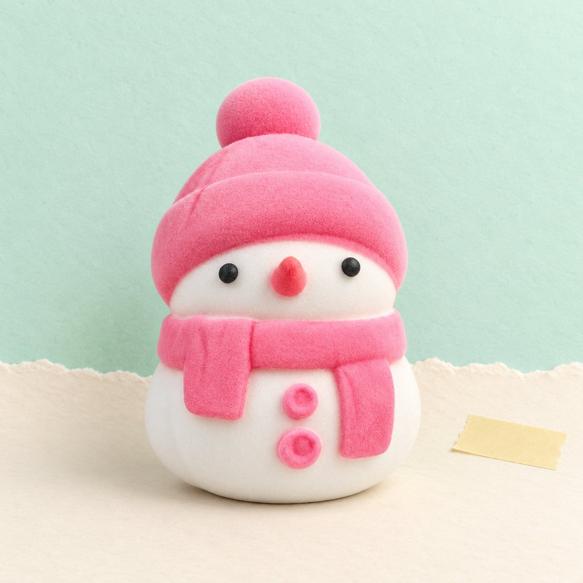 Squishy de muñeco de nieve slow rising, suave como un mochi, en rosa y con bolsa, sobre papel pastel