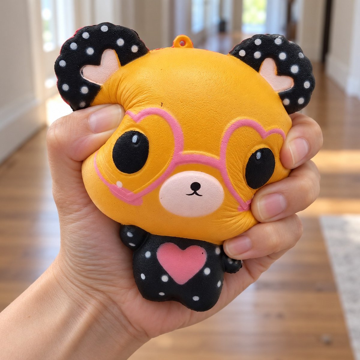 Mjuk och skön att krama: squishy nalle med hjärtglasögon i orange i handen