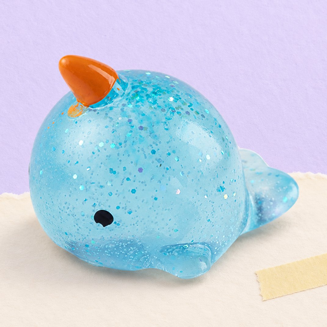 Squishy narvalo con glitter fotografato su carta color pastello