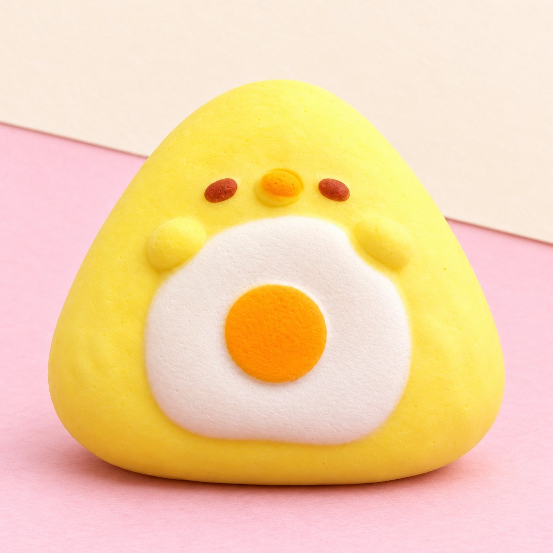 Squishy onigiri slow rising: pulcino giallo con uovo all'occhio di bue, su carta pastello