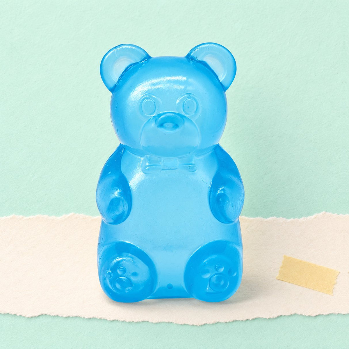Squishy de osito de gominola slow rising en azul, sobre papel pastel