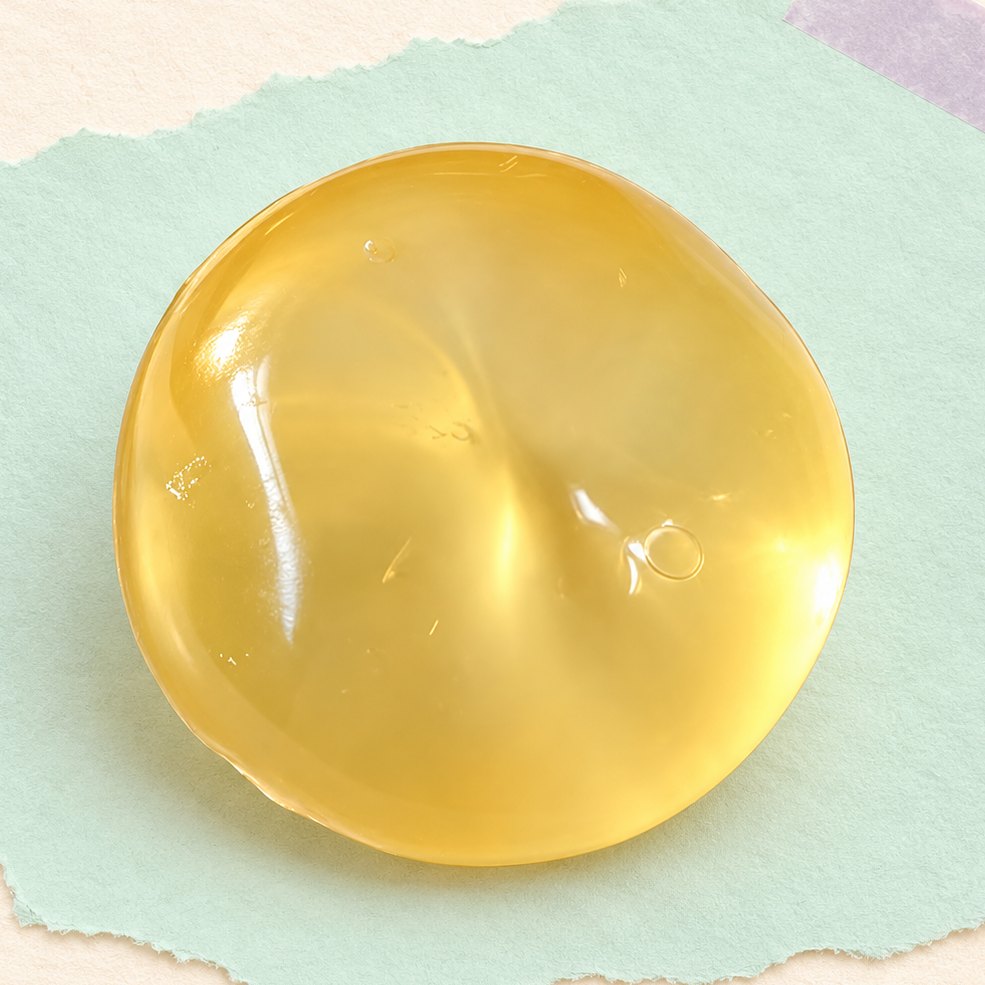 Żółty squishy owoc coconut oil, 6 cm, na pastelowym papierze