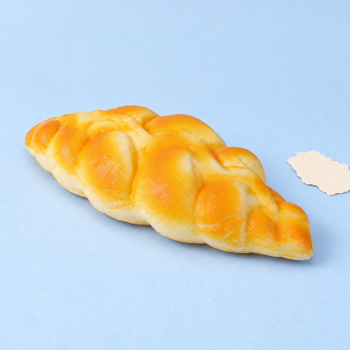 Squishy pan trenzado, 19 cm, sobre papel pastel