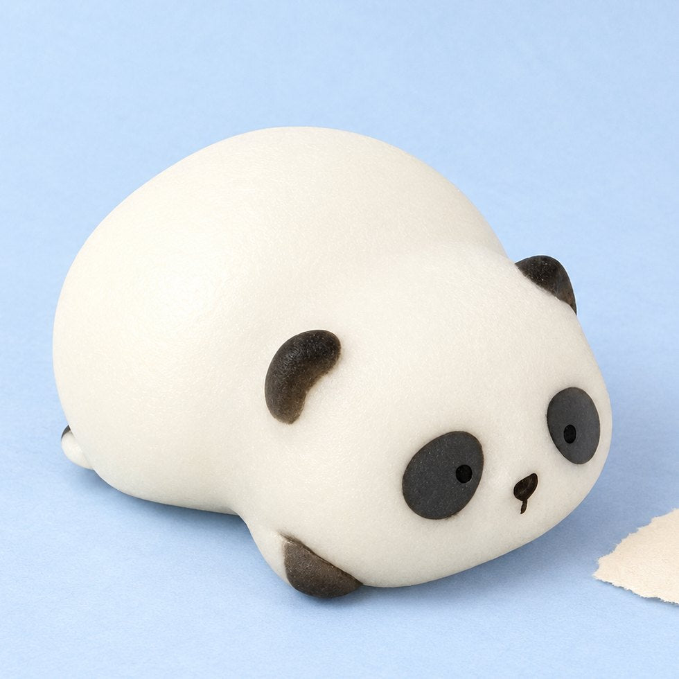 Squishy panda deitado numa caixa de oferta, sobre papel cor pastel