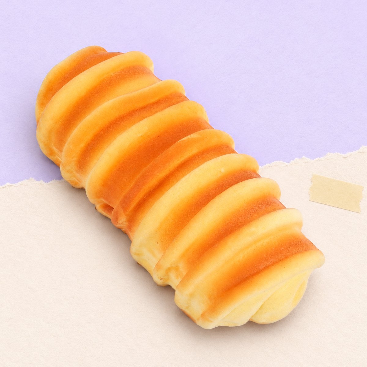 Squishy pão lagarta de 15 cm sobre papel cor pastel