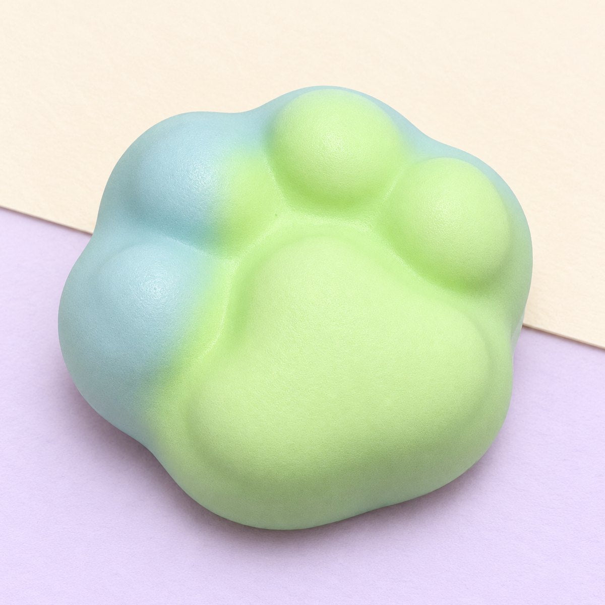 Squishy pata de gato crunchy de 6 cm, em verde, sobre papel pastel