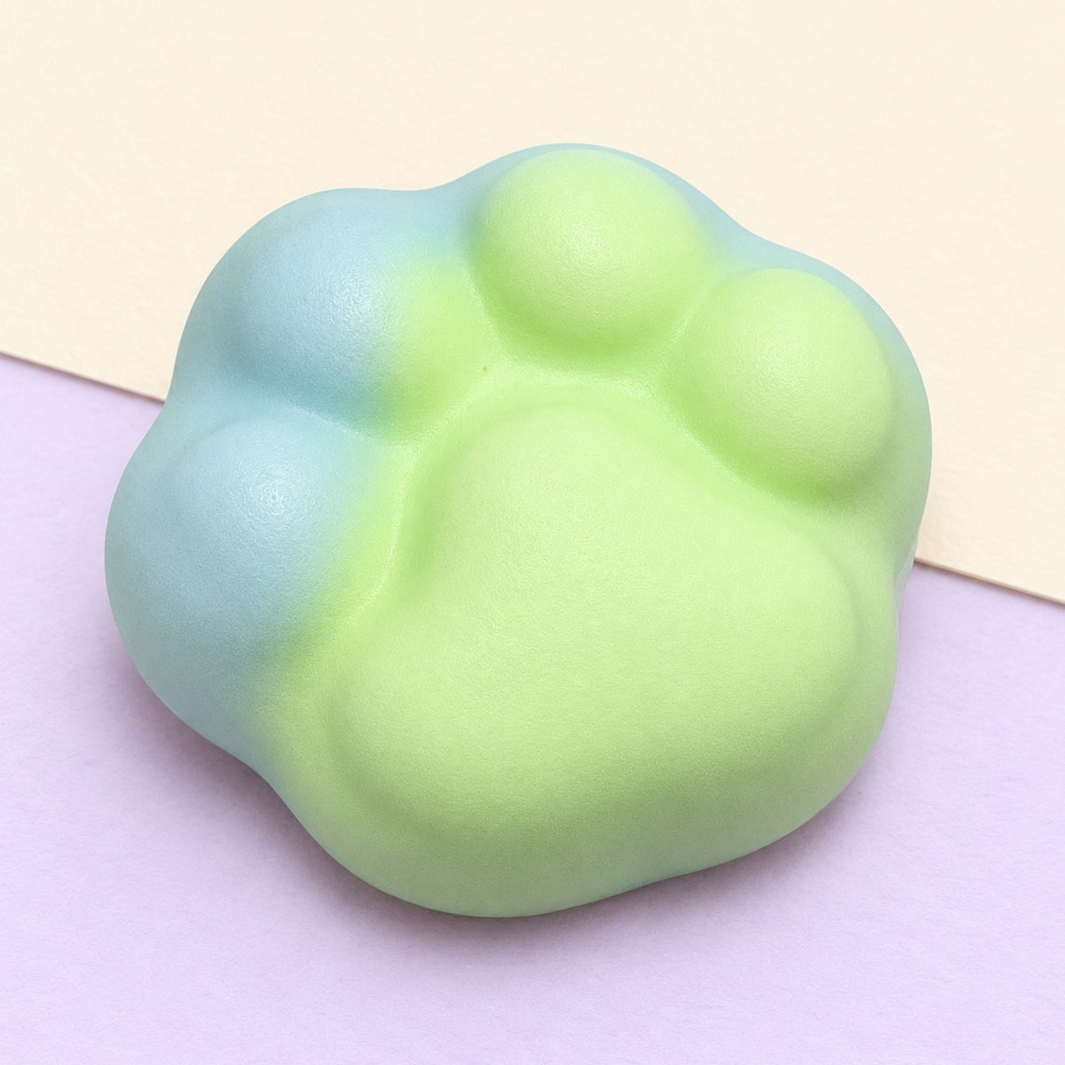 Squishy crunchy de pata de gato de 6 cm en verde, sobre papel pastel