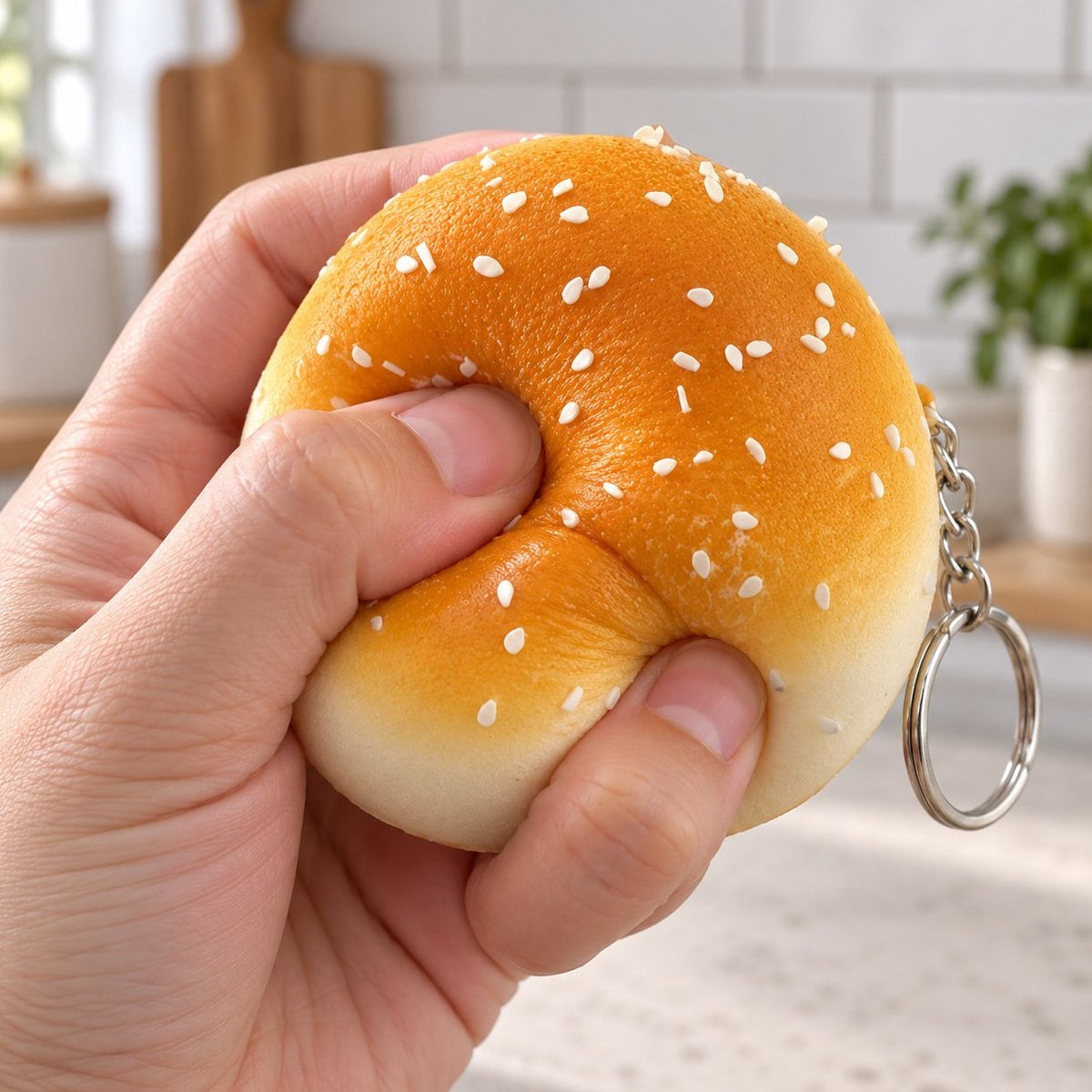 Main qui presse un squishy porte-clés pain au sésame de 7 cm