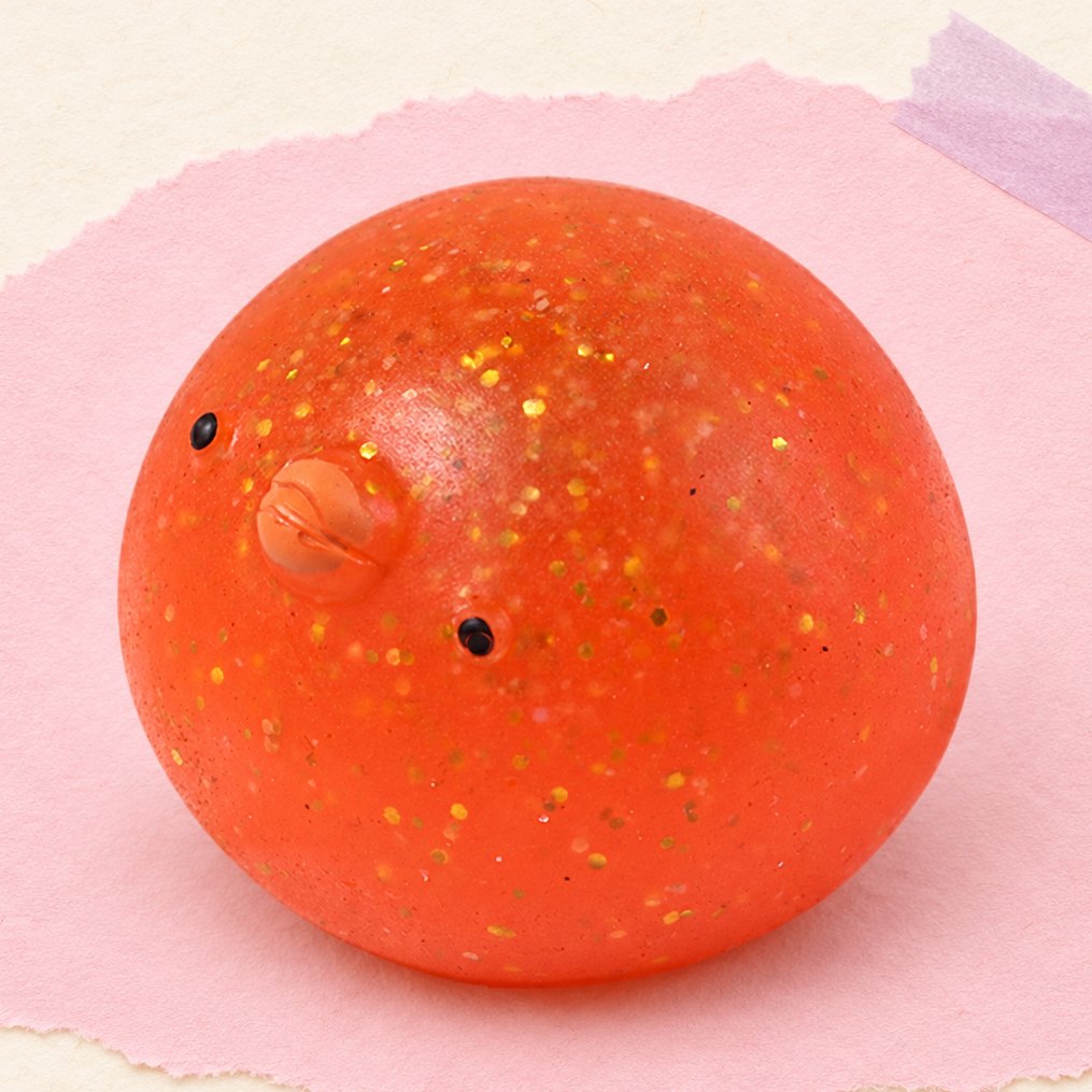 Squishy poussin mochi avec paillettes, posé sur papier pastel