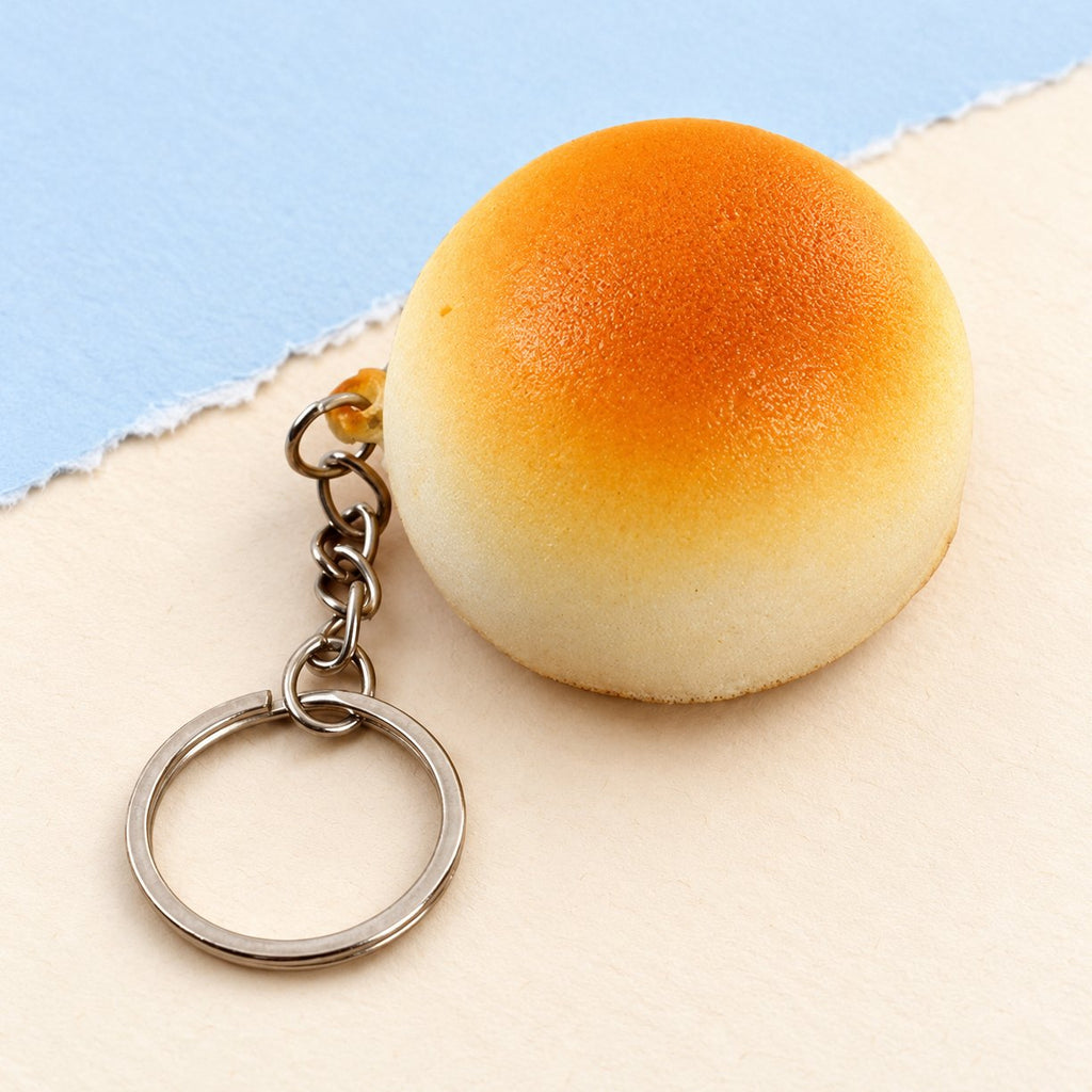 Squishy přívěsek na klíče, zlatavá houstička 4 cm, na pastelovém papíře