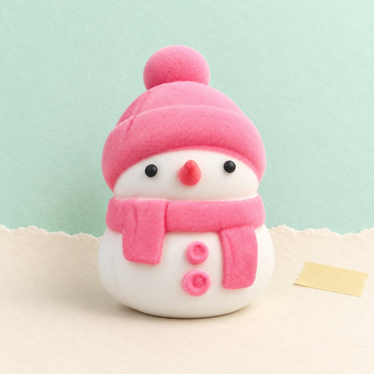 Squishy pupazzo di neve rosa nella sua bustina mochi slow rising, foto del prodotto su carta pastello