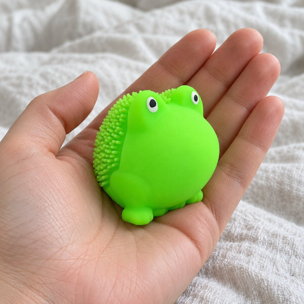 Squishy rana con pinchos sostenido hacia la cámara, en primera persona