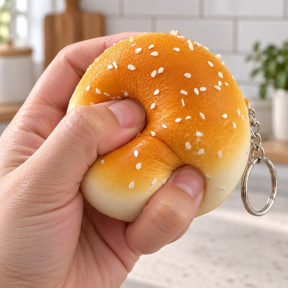 Slow Rising Squishy Schlüsselanhänger als Brötchen (mit Sesam, 7 cm) wird mit der Hand zusammengedrückt