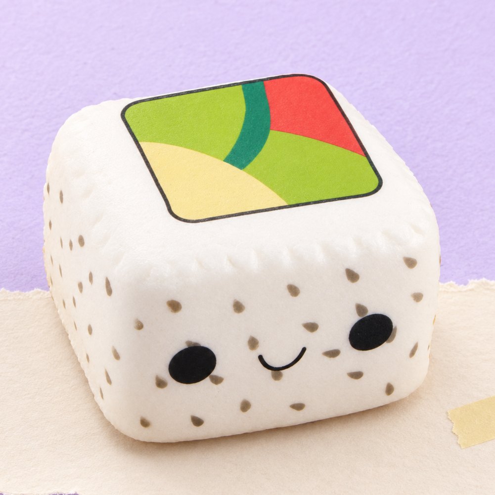 Squishy de sushi kawaii slow rising de arroz blanco con sésamo negro, sobre papel pastel