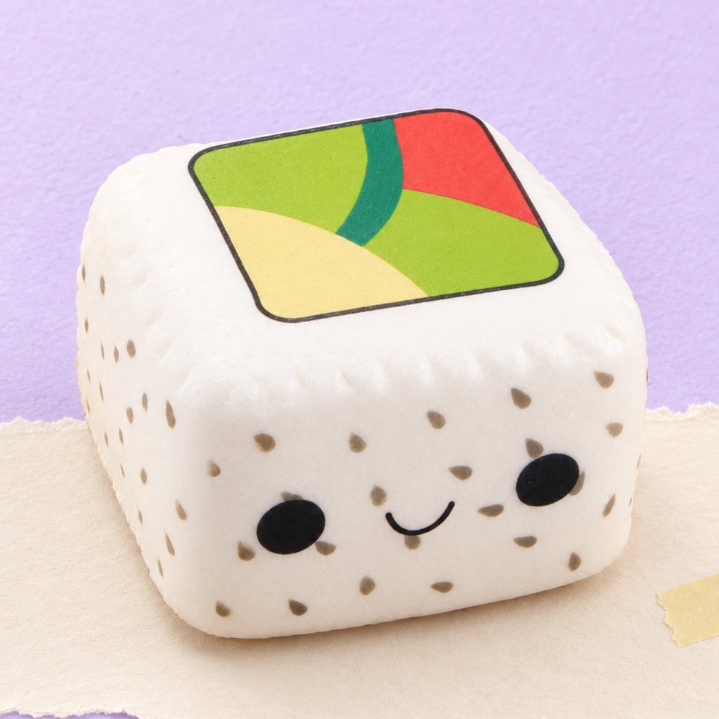 Squishy sushi kawaii s bílou rýží a černým sezamem na pastelovém papíře