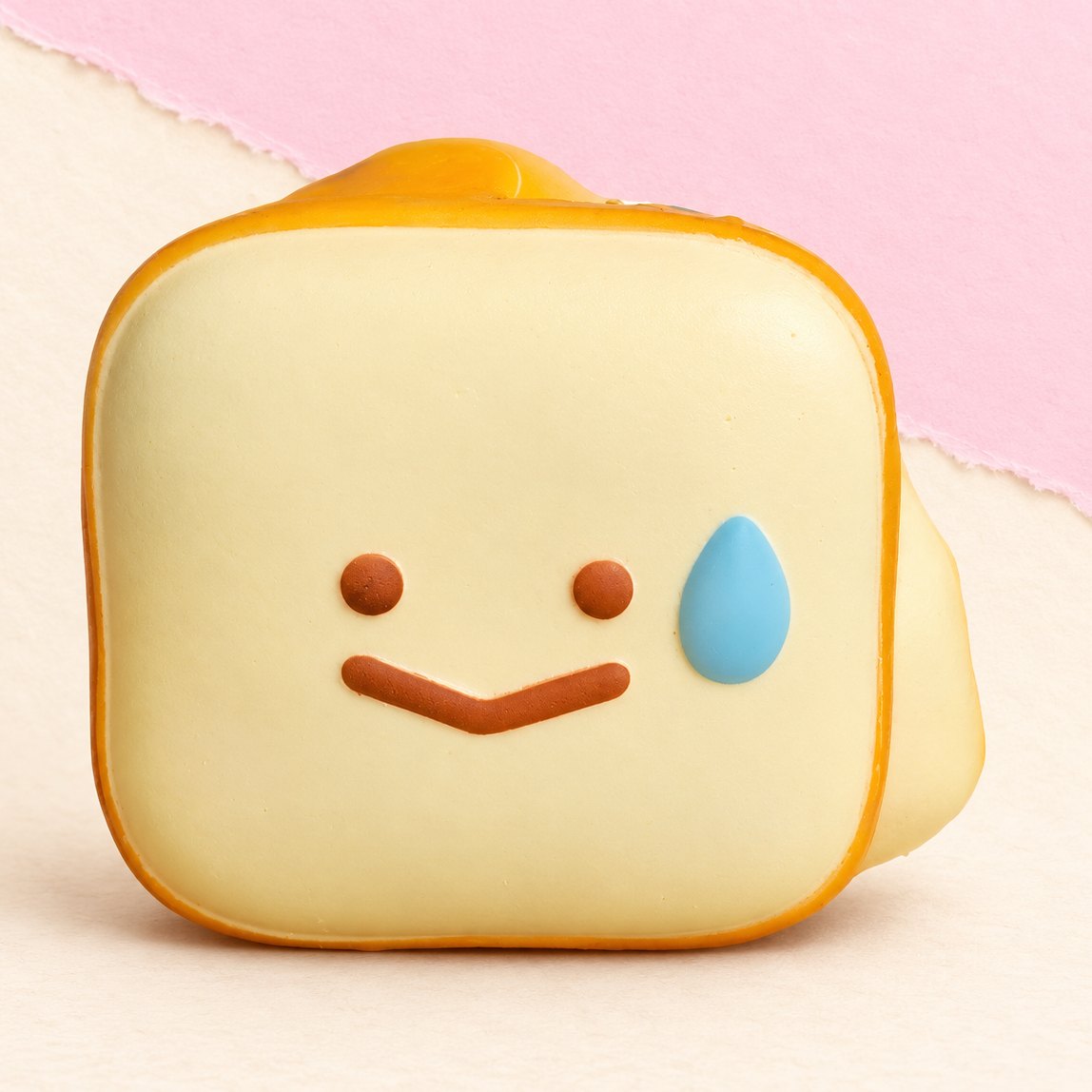 Squishy tostada kawaii con carita sonriente sobre papel pastel
