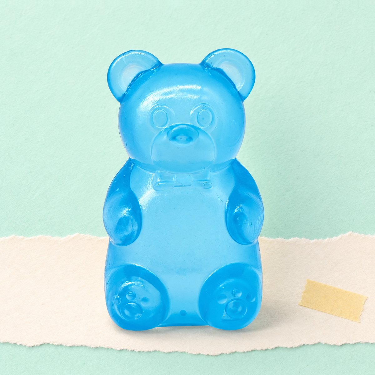 Squishy ursinho de goma slow rising em azul, sobre papel pastel