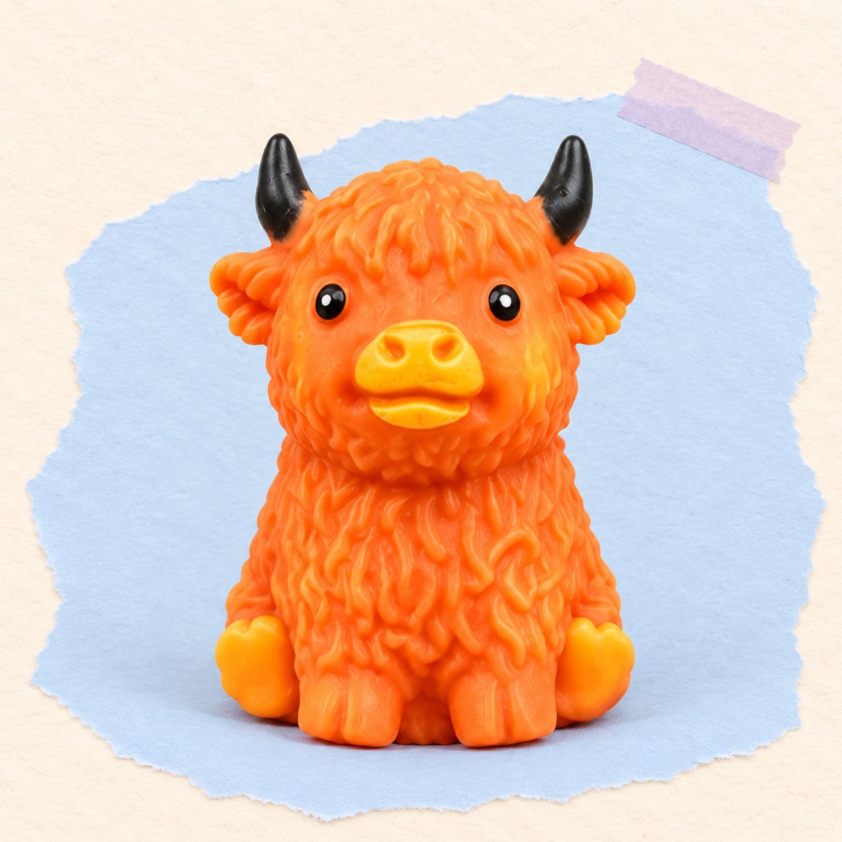 Squishy vache highland crunchy brun orangé, garni de blocs qui craquent, sur papier pastel