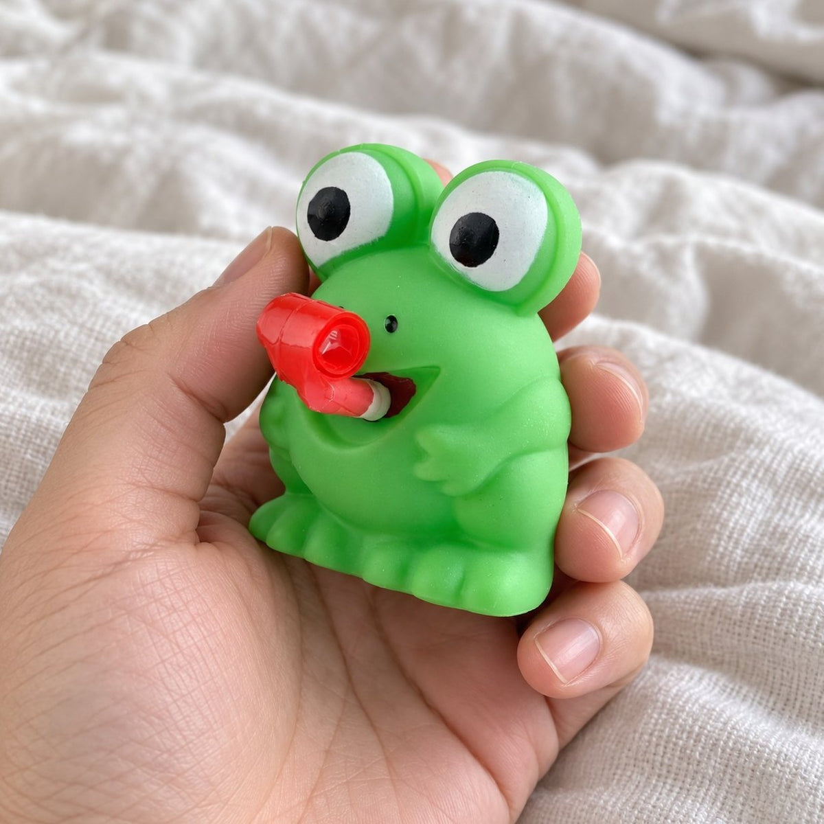 Squishy žabka nebo dino, varianta žabka, z pohledu první osoby, držená před fotoaparátem
