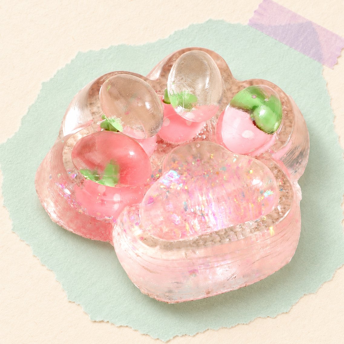 Squishy zampa di gatto glitter con frutta, rosa fragola, 7 cm, su carta pastello