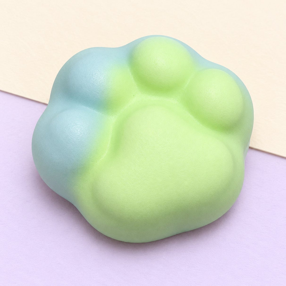 Squishy zampa di gatto mini verde da 6 cm fotografato su carta color pastello