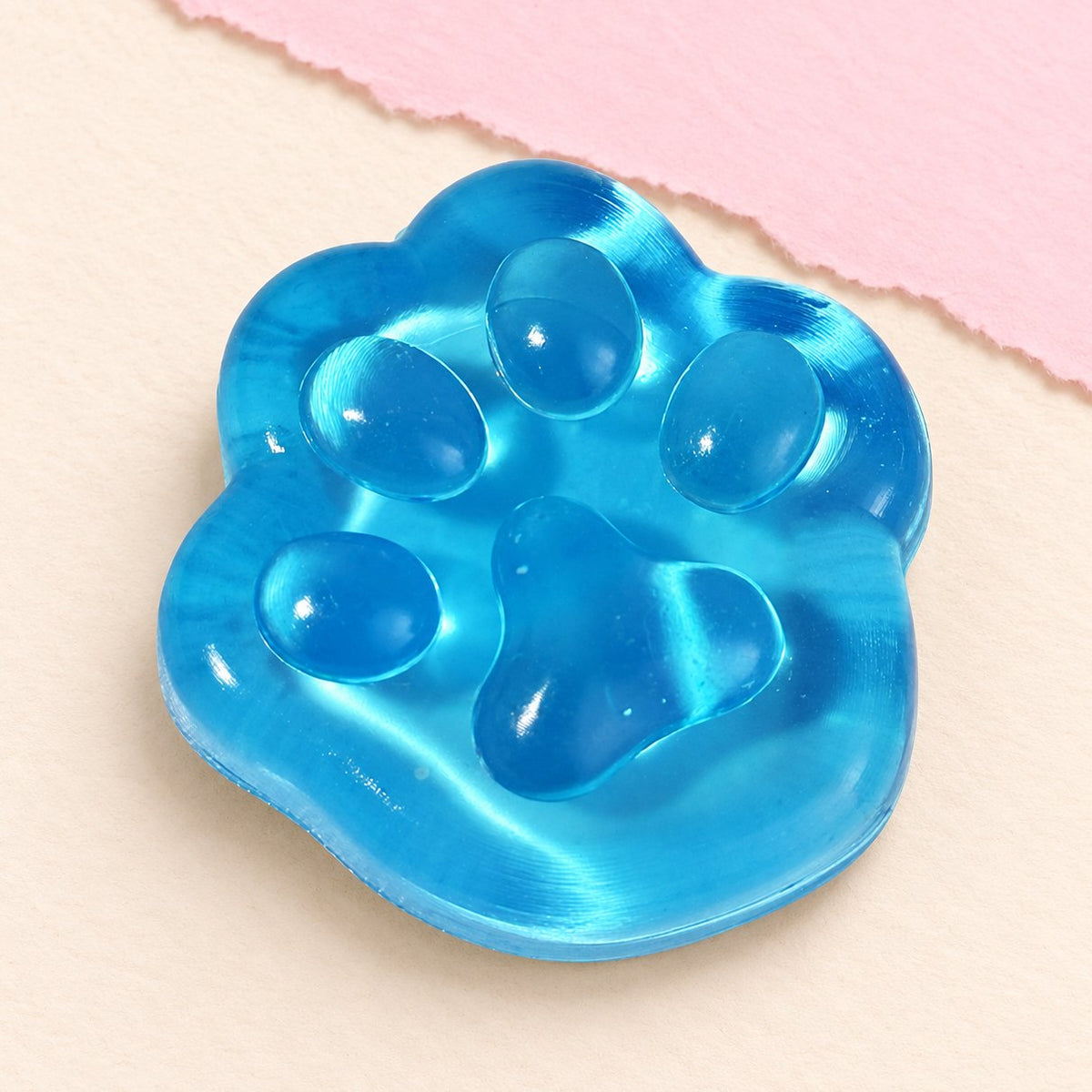 Squishy zampa di gatto mini gelatinoso, blu, da 4 cm su carta pastello