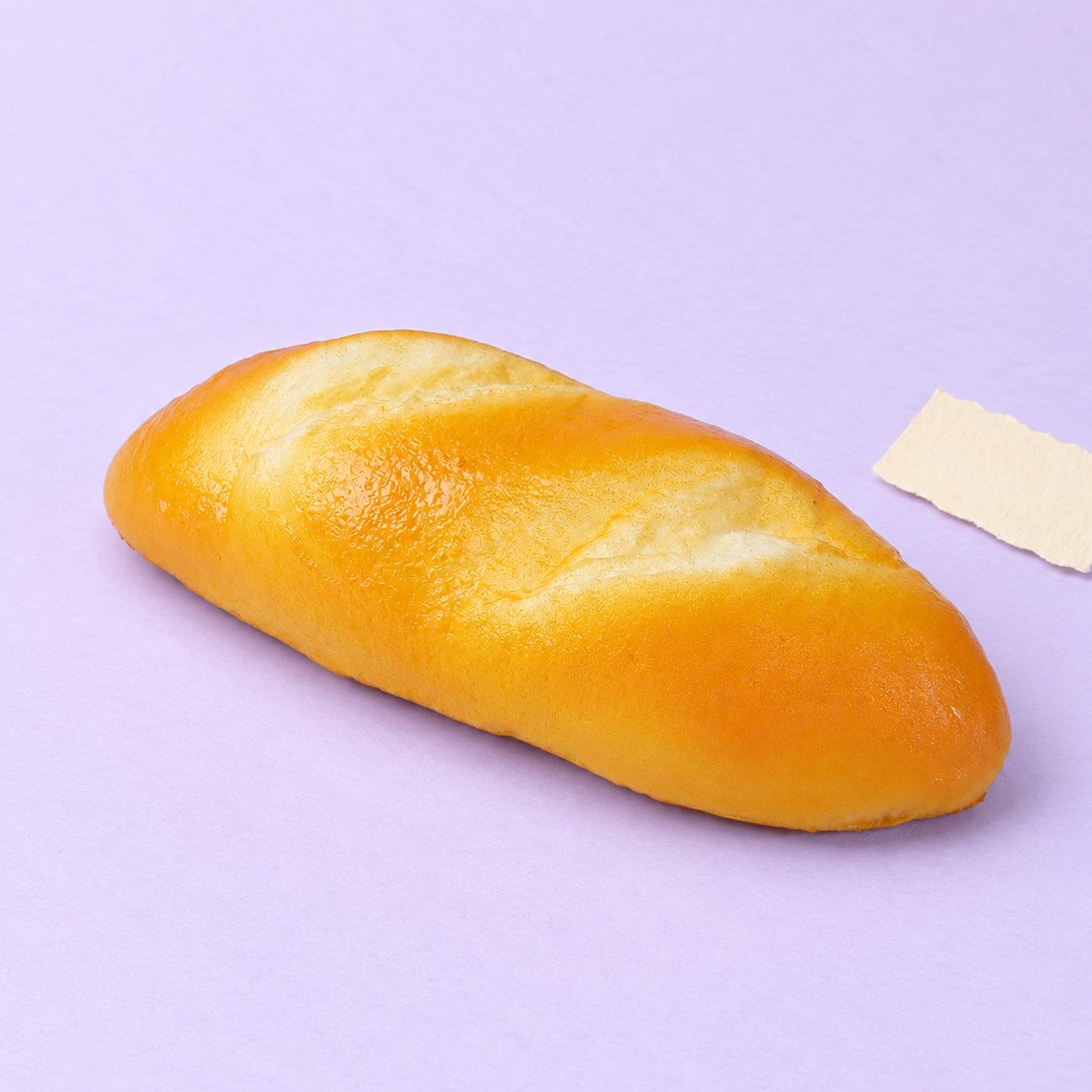 Stokbroodje squishy: lang en zacht melkbroodje van 18 cm op pastelkleurig papier