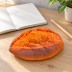 Baked Sweet Potato Squishy, Slow Rising PU, on a desk with a notebook and pencil